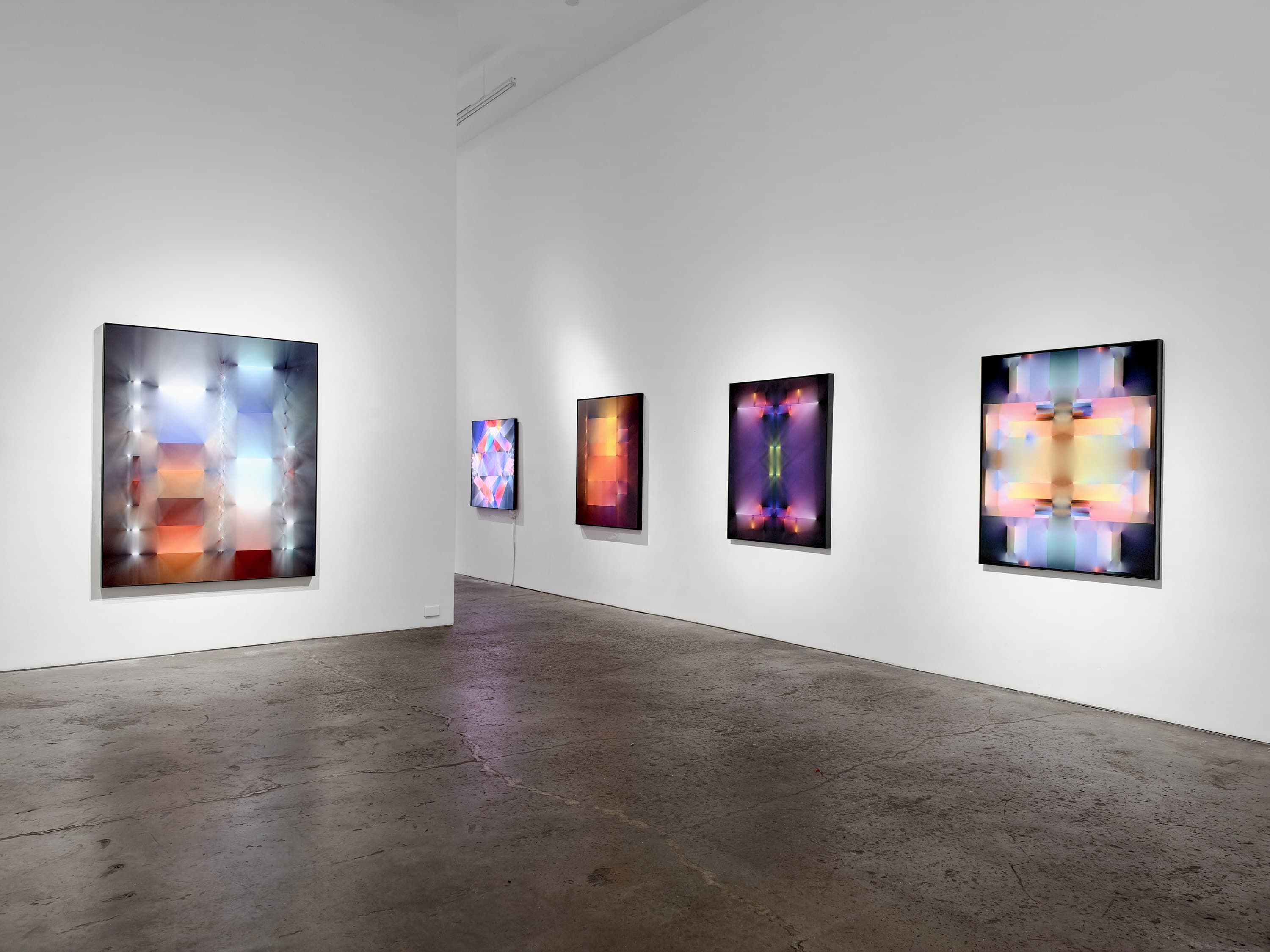 Five large prints from What Light May Be hung across two white walls at Heft, New York.